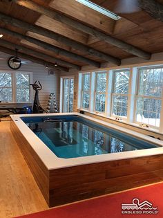 an indoor hot tub in the middle of a wood floored room with large windows