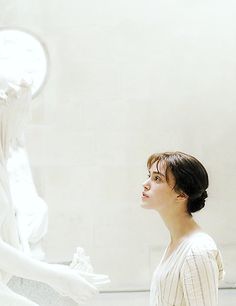 a woman standing in front of a white statue