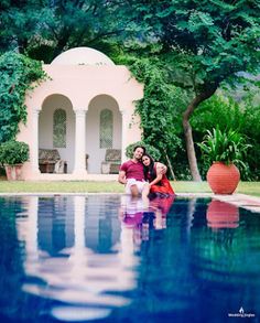 a man and woman sitting on the edge of a pool