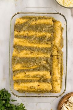 an enchilada in a glass dish next to other ingredients on a white counter