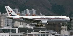 an airplane is taking off from the runway in front of some tall buildings and mountains