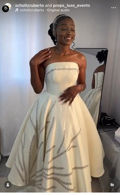 a woman wearing a white dress and veil in front of a mirror