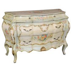 an old dresser with flowers painted on the top and drawers, is shown against a white background