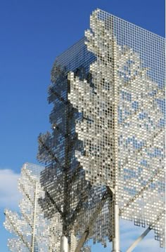 a metal structure with many squares on it's sides and trees in the background