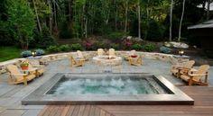 an outdoor hot tub surrounded by chairs and fire pit in the middle of a wooden deck