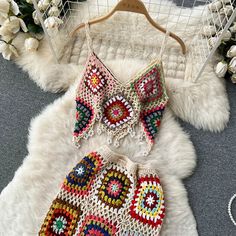 two pieces of crocheted clothing sitting on top of a white fur covered floor