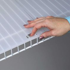 a woman's hand is on the edge of a white plastic shelf with strips