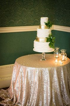 a white wedding cake sitting on top of a table next to two glasses and candles