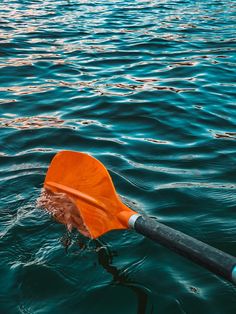 an orange kayak floating on top of the ocean next to a blue buoy