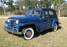 an old blue car is parked in the grass