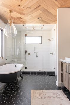 a bathroom with black and white tile flooring and wood paneled ceiling above the bathtub