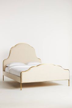 a white bed with gold trim and headboard