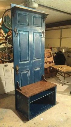 a blue door sitting inside of a garage next to a wooden table and bench with wheels on it