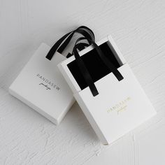 two white boxes with black ribbons on them