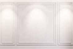 an empty white room with three lights on the wall