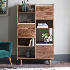 a green chair sitting next to a tall wooden shelf