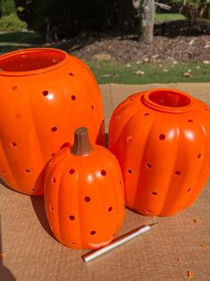 three orange pumpkin shaped vases sitting on top of a table