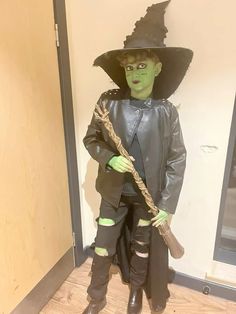 a young boy dressed as a witch holding a broom