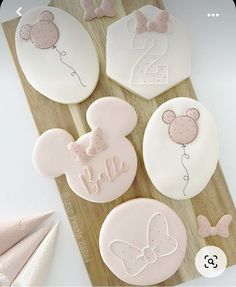 some decorated cookies on a cutting board with pink and white icing in the shape of minnie mouses