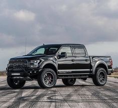 a black truck parked on top of a dirt road