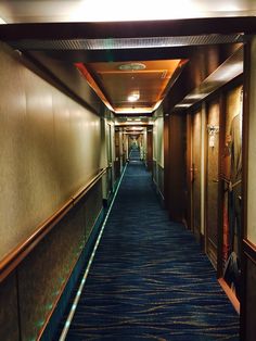 an empty hallway with blue carpet and wooden walls