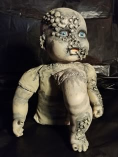 a creepy looking doll with blue eyes sitting on a black surface