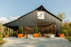 a barn with tables and chairs set up for an outdoor wedding reception in the sun