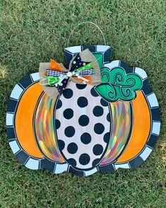 a painted pumpkin on the grass with a bow