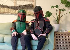 two people dressed as boba fett sit on a couch