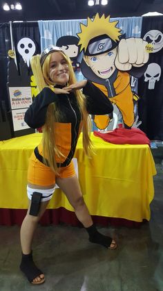 a woman posing in front of a table with anime characters on it's walls