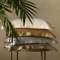 four pillows stacked on top of each other in front of a palm tree and wall