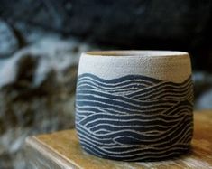 a white and black vase sitting on top of a wooden table