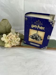 a harry potter book sitting on top of a wooden shelf next to a fake flower