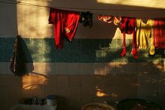 clothes hanging on a line in a kitchen with sunlight coming through the window and casting shadows onto the tiles