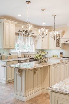 a large kitchen with an island and chandelier hanging from it's ceiling