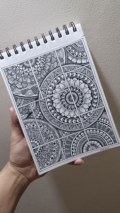 a hand holding up a spiral notebook with an intricate design