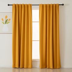 a yellow curtain hanging on the side of a window in front of a white wall