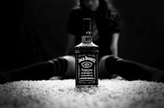 a bottle of jack daniels whiskey sitting on the floor next to a woman's legs