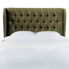 a bed with a green headboard and white sheets