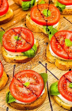 sandwiches with tomatoes and basil on them are arranged on a wooden cutting board, ready to be served