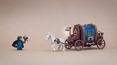 a toy horse drawn carriage with two figurines on the ground next to it