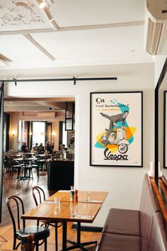 an empty restaurant with tables and chairs in front of the wall hanging on the wall