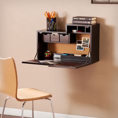 a desk with a chair underneath it in front of a wall mounted bookcase and computer monitor