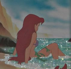 the little mermaid is sitting in the water with her feet on the sand and looking at something