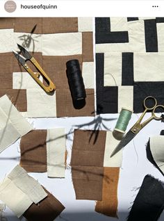 scissors, thread, and fabric laid out on a white tablecloth with brown squares