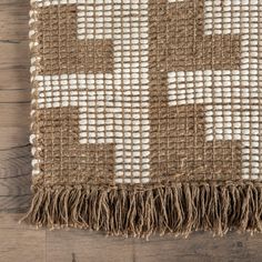 a brown and white rug with fringes on top of wooden flooring next to a wall