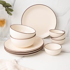 a table topped with plates and cups next to a glass filled with wine on top of a white counter