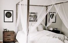 black and white photograph of a bedroom with four poster bed, dressers and pictures on the wall