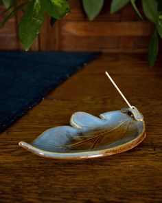 a ceramic object on a wooden table next to a potted plant and blue rug