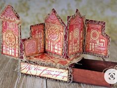 an open box with red and gold paper cutouts on it, sitting on top of a wooden table